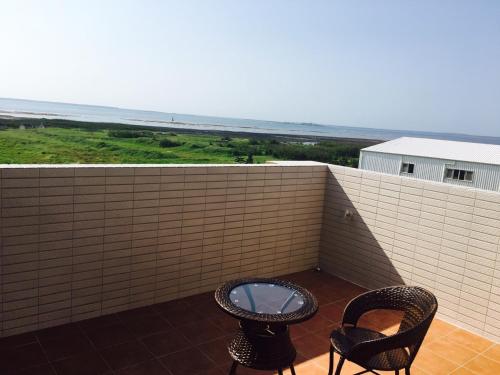 Dos sillas y una mesa en un balcón con vista al mar. en Miyue B&B, en Magong