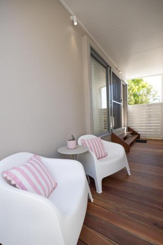 a white bedroom with a bed and two chairs at Aloha Byron Bay in Byron Bay