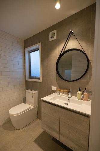 a bathroom with a sink and a toilet and a mirror at Aloha Byron Bay in Byron Bay