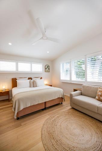 a white bedroom with a bed and a couch at Aloha Byron Bay in Byron Bay