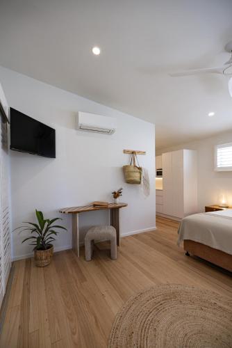 a bedroom with a bed and a desk and a television at Aloha Byron Bay in Byron Bay