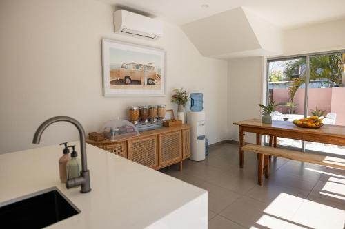 a kitchen with a table and a counter top at Aloha Byron Bay in Byron Bay