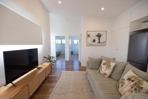 a living room with a couch and a flat screen tv at Aloha Byron Bay in Byron Bay