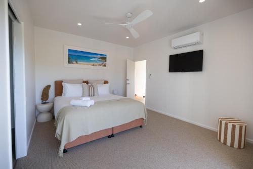 a bedroom with a bed and a flat screen tv at Aloha Byron Bay in Byron Bay