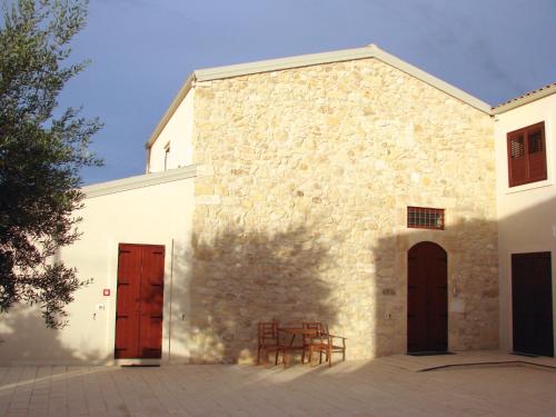 une grande église blanche avec deux portes et une chaise dans l'établissement Kinanto Bioresort, à Ispica