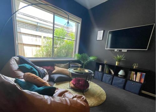 a living room with a couch and a flat screen tv at Tropical Ocean Vibe Fully Aircon House in Strathpine