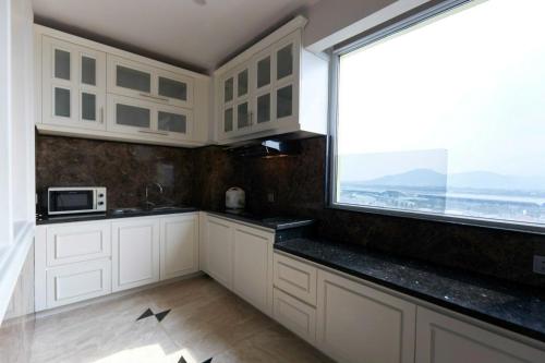 a kitchen with white cabinets and a large window at Samdi Premium - Near Da Nang International Airport in Da Nang