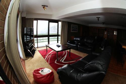 a living room with a black leather couch and a table at Alpine Retreat Mt Buller in Mount Buller
