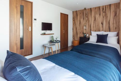 a hotel room with two beds and a television at Villa Penthouse Tenma in Osaka