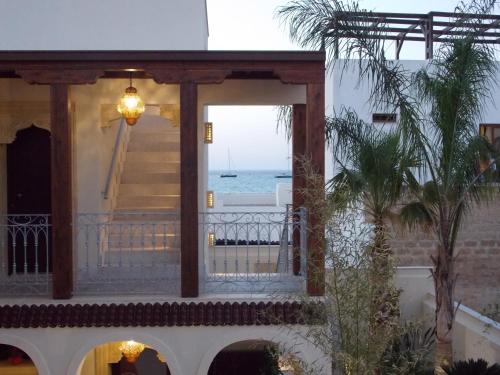 a house with a balcony with a view of the ocean at RIAD Comfort Rooms in San Vito lo Capo