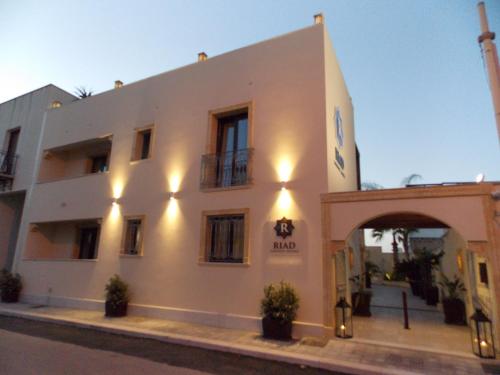 a white building with an arch in front of it at RIAD Comfort Rooms in San Vito lo Capo