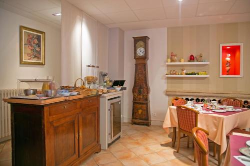 a kitchen with a table and a grandfather clock at Logis Hôtel Auberge de la Rose in Doué-la-Fontaine