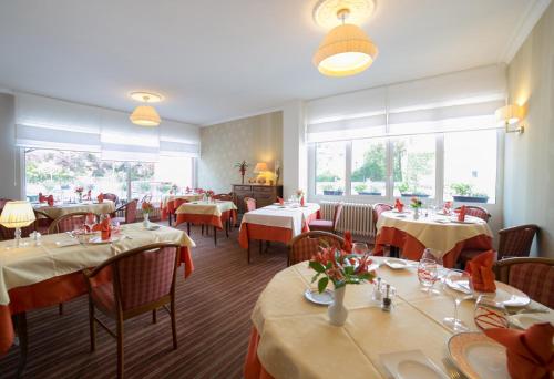 un comedor con mesas, sillas y ventanas en Logis Auberge de la Rose, en Doué-la-Fontaine