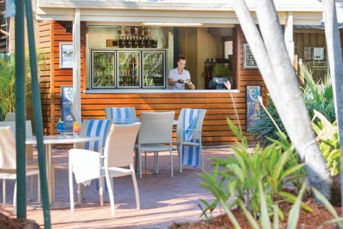a man standing behind a bar with chairs and tables at The Leea Resort Darwin in Darwin