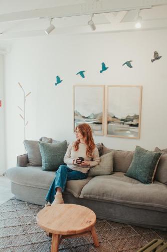 a woman sitting on a couch in a living room at The Quarters in Turangi