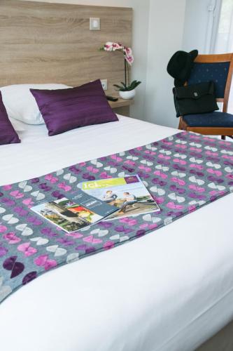 a bed with a quilt on top of it at Logis Hôtel Auberge de la Rose in Doué-la-Fontaine