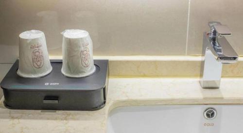 two cups sitting on top of a kitchen sink at City Comfort Inn Changsha South Railyway Station West Square in Changsha