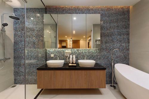 富国BayGi Phu Quoc Hotel的配有两个水槽、一个浴缸和一面镜子的浴室