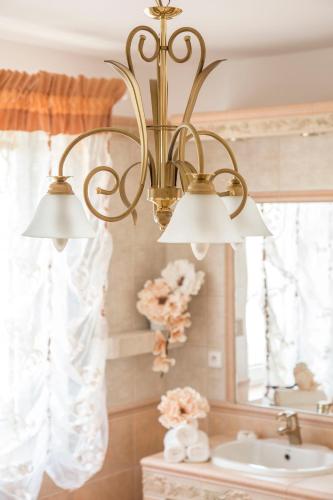 a chandelier in a bathroom with a sink and a mirror at Villa Grande - Apartmány in Olomouc