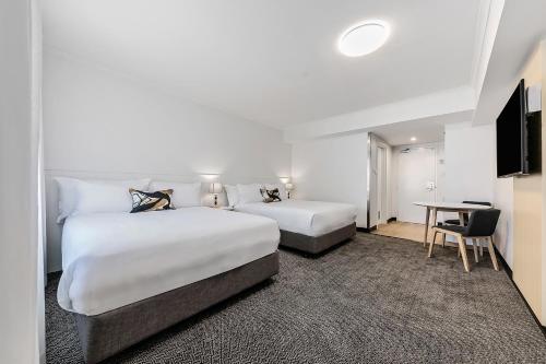 a hotel room with two beds and a desk at The Leea Resort Darwin in Darwin
