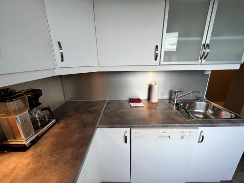 a kitchen with white cabinets and a sink at Central trainstation apartment in Narvik