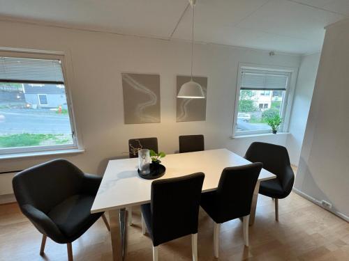 a dining room with a white table and black chairs at Central trainstation apartment in Narvik
