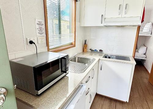 a small kitchen with a microwave and a sink at BIG4 Rutherglen Holiday Park in Rutherglen