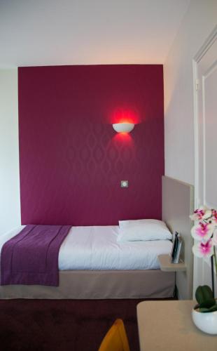 a bedroom with a purple wall with a bed at Logis Hôtel Auberge de la Rose in Doué-la-Fontaine