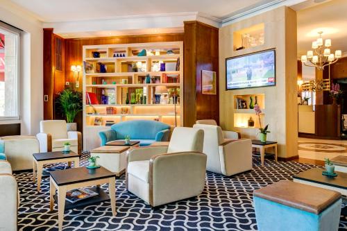 a lobby with couches and tables and a tv at Hotel Eden in Geneva