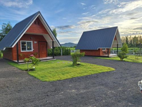 a house with a gambrel roof and a small yard with a grass at บ้านน้ำผึ้งโฮมสเตย์ in Suan Phung