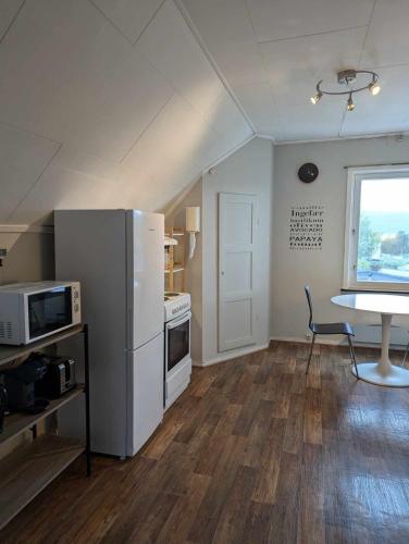 a kitchen with a refrigerator and a table in a room at Railway central loft apartment in Narvik