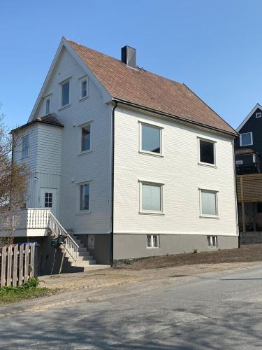 a large white house with a staircase next to a street at Railway central loft apartment in Narvik