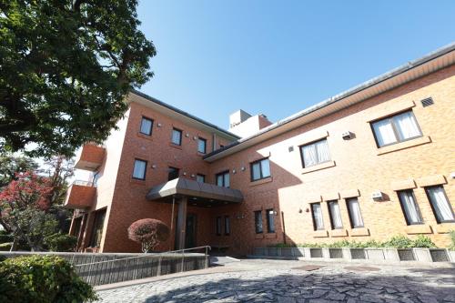 a large brick building with a tree in front of it at KKR Hotel Nakameguro in Tokyo