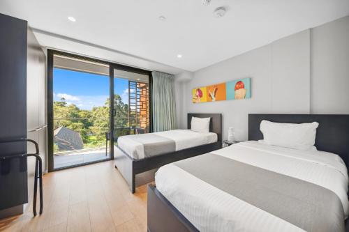 a bedroom with two beds and a large window at Studio 8 Residences - Adults Only in Sydney