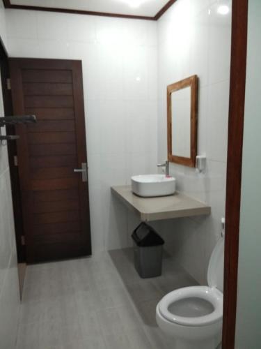 a bathroom with a toilet and a sink and a mirror at C'man Guest House in Mantaak