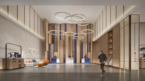 a man walking in a large room with chandeliers at Holiday Inn Express Langfang Sanhe by IHG in Sanhe