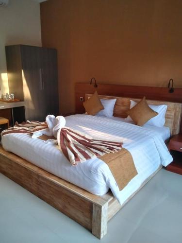 a large bed with white sheets and pillows at C'man Guest House in Mantaak