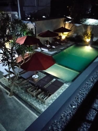 a pool at night with umbrellas and chairs at C'man Guest House in Mantaak