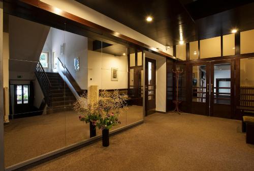 a lobby with a staircase and a vase of flowers at Parkhotel Skalní město in Jičín