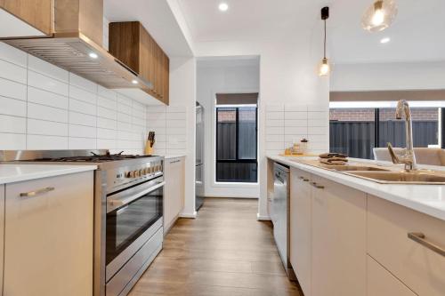 a kitchen with white cabinets and a sink and a stove at Ravish in Paynesville