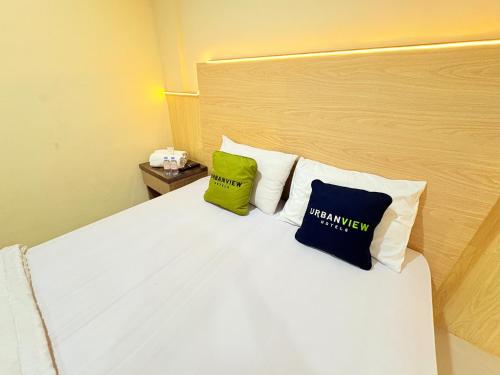 a bedroom with a white bed with two pillows on it at Urbanview Hotel Ling near Jawa Timur Park 2 in Tlekung