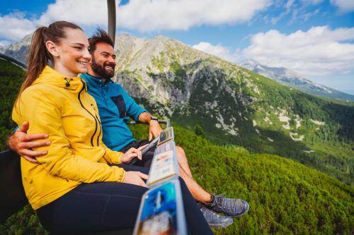 a man and a woman sitting on a ski lift at Hotel FIS in Štrbské Pleso