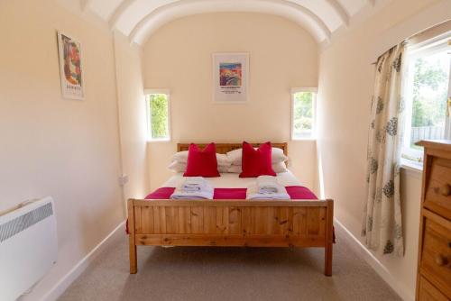 une chambre avec un lit avec des oreillers rouges dans l'établissement Railway Carriages, à Hinton Admiral Station