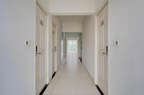 a hallway with white walls and white floors and doors at Super Hotel O KSR Bengaluru City Junction Formerly Gurudev Residency in Bengaluru