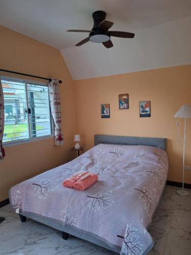 a bedroom with a bed with a ceiling fan at บ้านน้ำผึ้งโฮมสเตย์ in Suan Phung