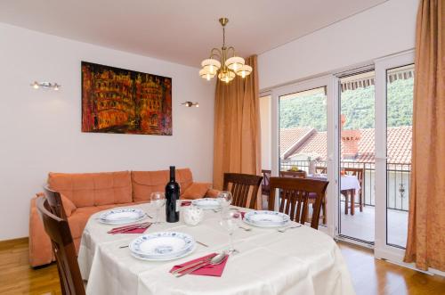 een eetkamer met een tafel met een witte tafeldoek bij Apartment Marela in Mokošica