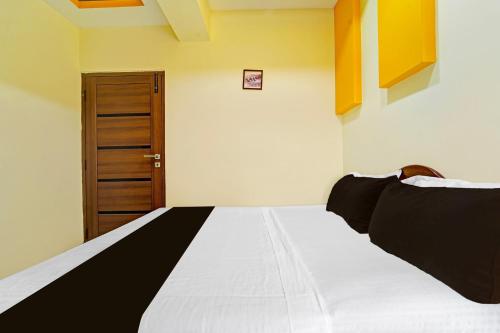 a bedroom with a large white bed and a wooden door at Super Hotel O Dindugal Bus Terminal Formerly GK Building in Dindigul