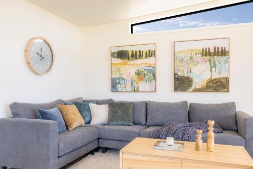 a living room with a couch and a clock on the wall at Wairo Beach Holiday Park in Lake Tabourie