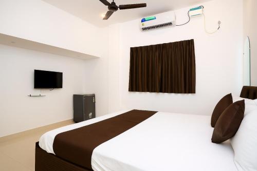 Un dormitorio blanco con una cama y un televisor. en Calangute Beach Home Away, en Calangute