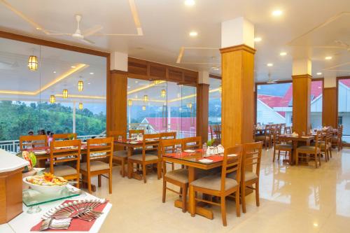 a restaurant with wooden tables and chairs and large windows at The Fog Munnar (Resort & Spa) in Munnar